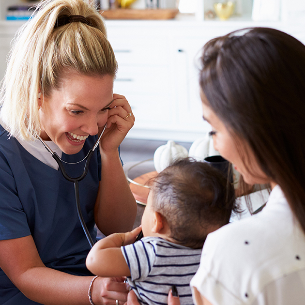 Home care physician smiling at a baby