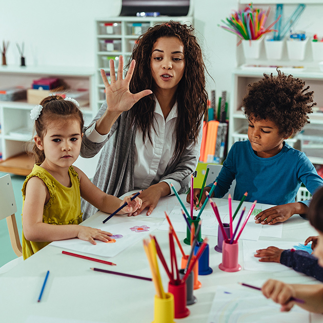 Female teacher coloring with two young students