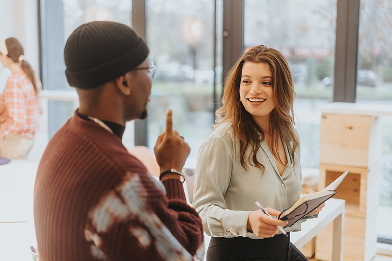 Young woman with notebook conducting research, meeting with advisor