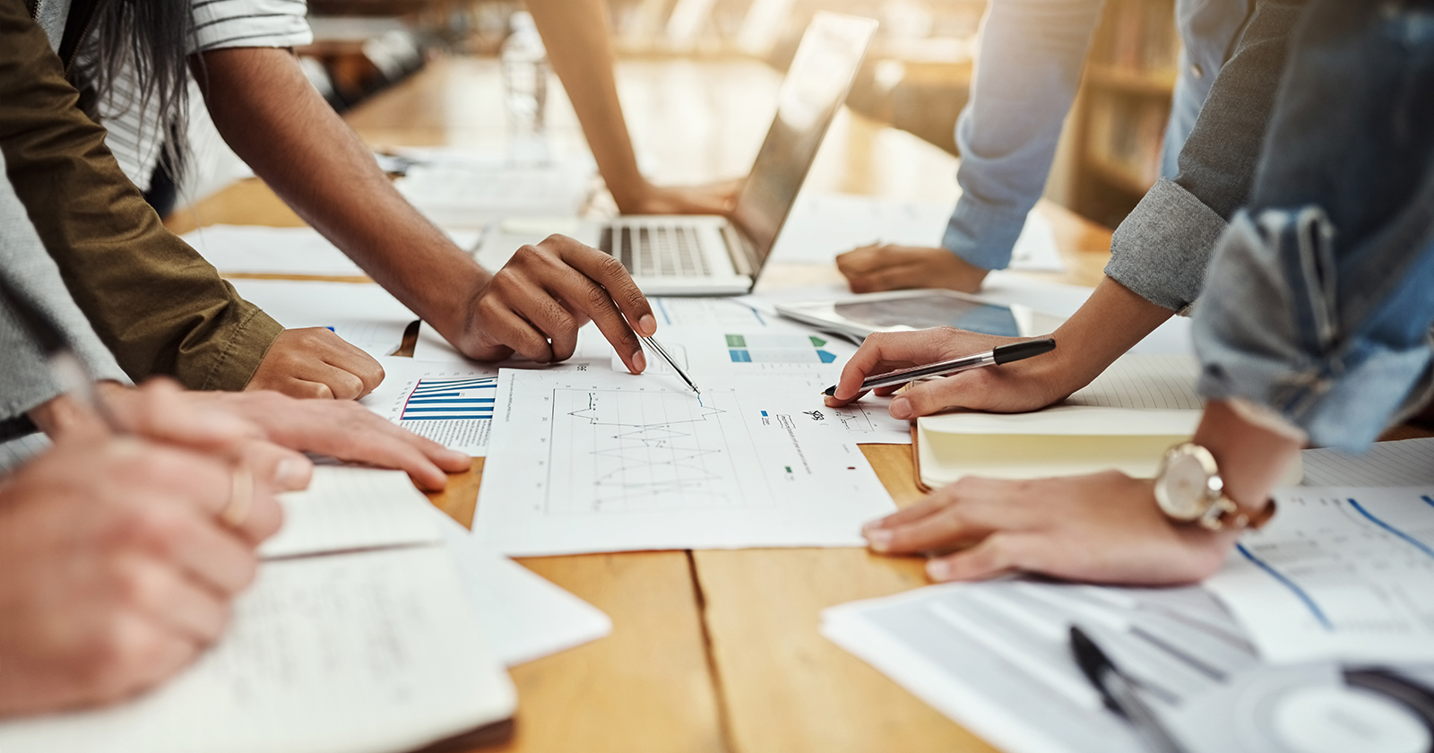 Colleagues lean over a table to view data on sheets of paper