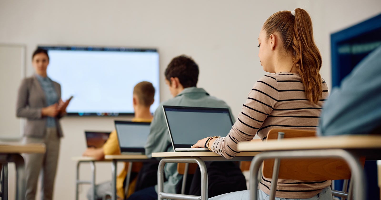 A group of high school students in a technology class, shown from behind