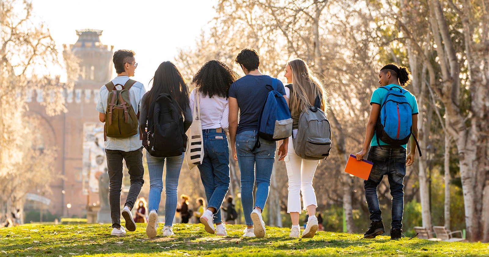 Rear view of college students walking outside 