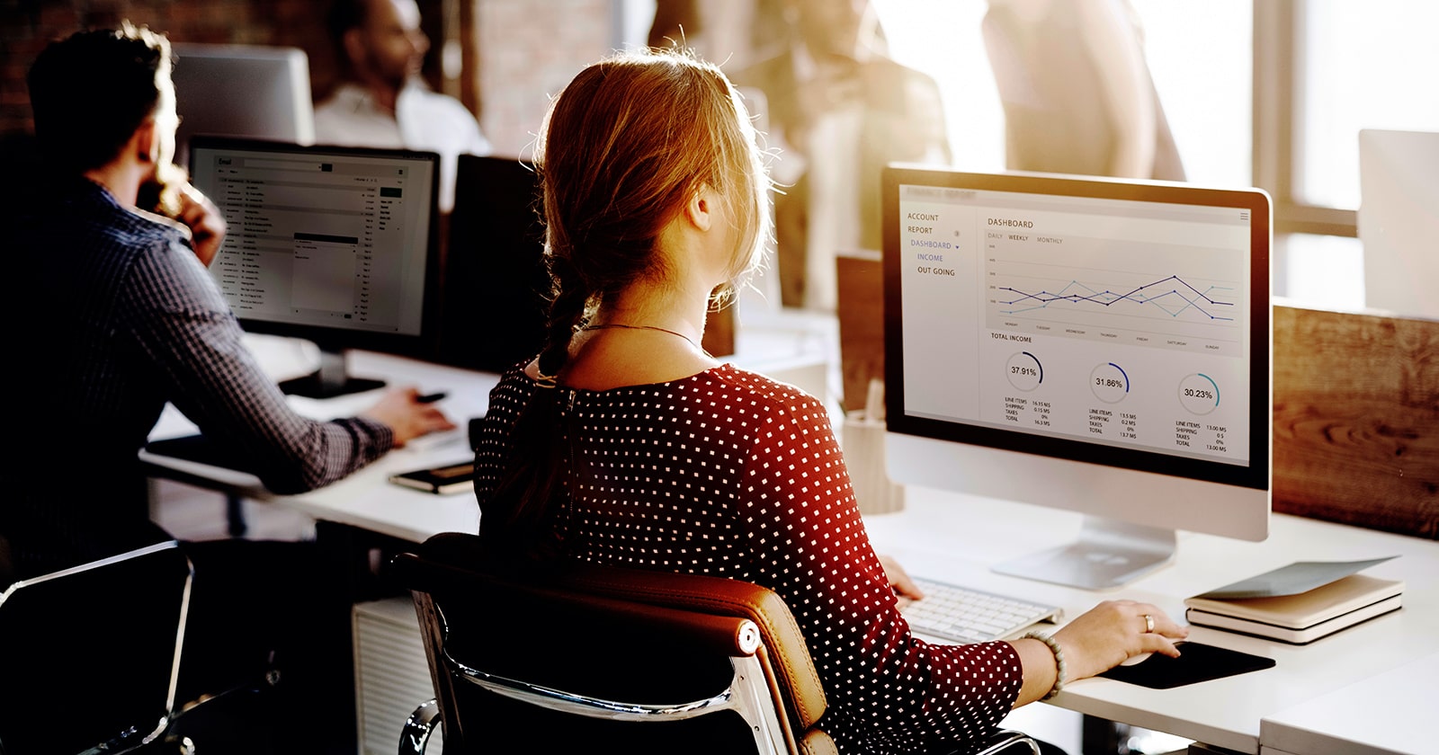 Woman shown from behind looking at a computer screen that shows data