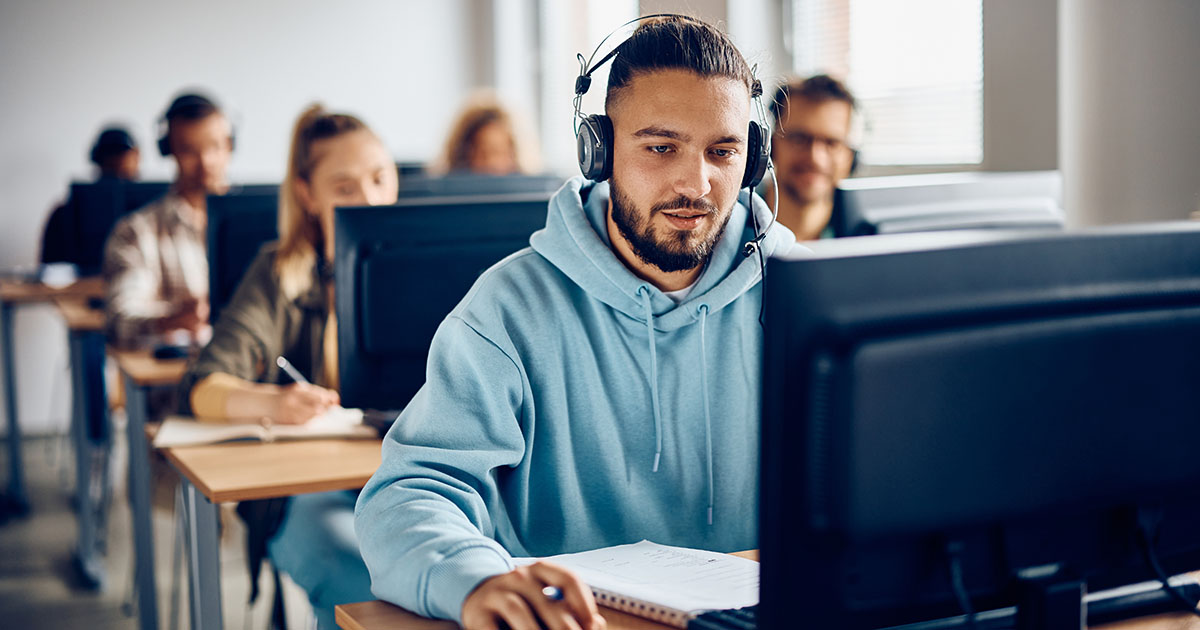 a man is sitting in a classroom in front of a computer