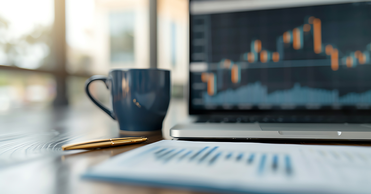 a cup in front of open laptop with graphs on a screen