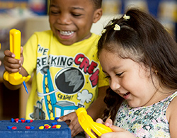 Pre-K boy and girl playing with toy hammers at school