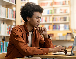 High school student in a library using a laptop