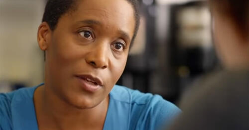 Black woman shown in close-up speaking to another woman