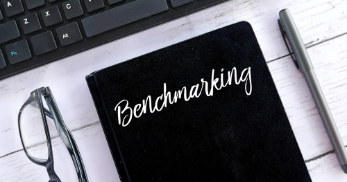 A book on a desk with the word "Benchmarking" written on its cover