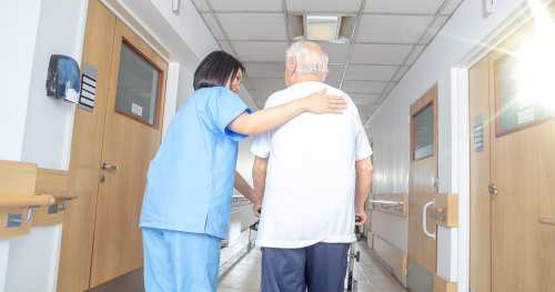Nurse's aid walking patient down a hospital hallway