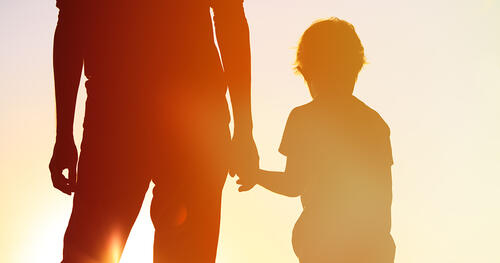 father is holding son by hand