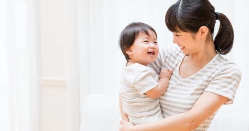 Young Asian mother holding and smiling at her infant