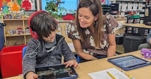 A teacher guides a student through an assessment test on a tablet computer