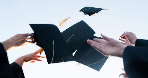 Hands of college graduates throwing caps in the air