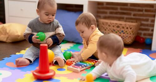 Three infants play with colorful toys 