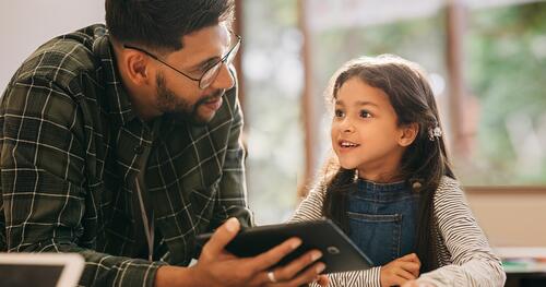 Pre-K instructor works with a student on a tablet
