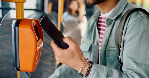 Close-up of man using phone to pay for a bus ride