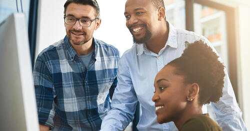 3 people college age looking at the computer monitor