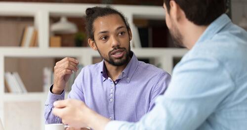 One man counsels another in a professional setting