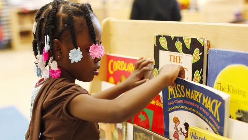 Young girl looks at books in a library