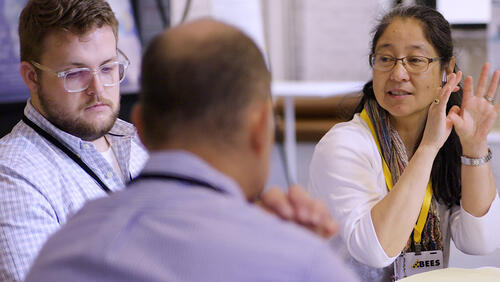 two men and a women are talking at the table