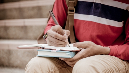 a student is writing in a notebook