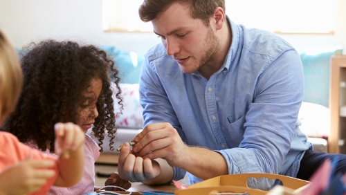 White male teacher helping young Black female student