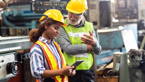 Two factory workers reviewing a tablet