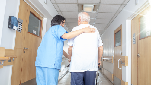 Nurse's aid walking patient down a hospital hallway