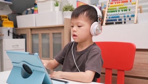 Pre-K child wearing headphones uses a tablet