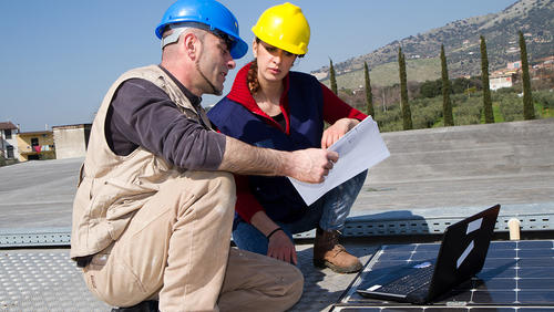 Older man instructing young women re solar system installation