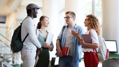 Diverse group of college students chatting in a library