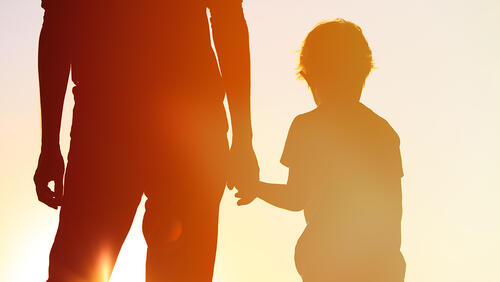 father is holding son by hand