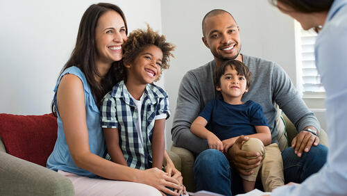 A family with two kids talking to a program staff