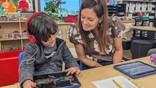 A teacher guides a student through an assessment test on a tablet computer
