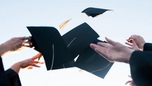 Hands of college graduates throwing caps in the air