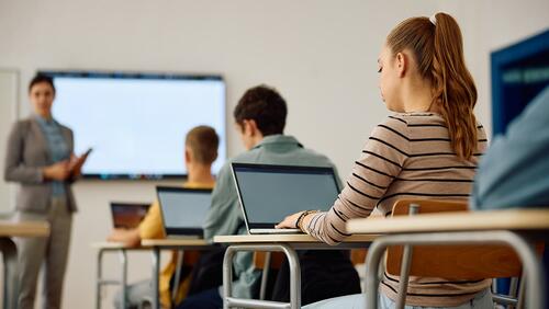 A group of high school students in a technology class, shown from behind