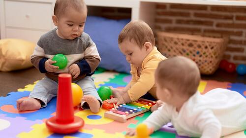 Three infants play with colorful toys 