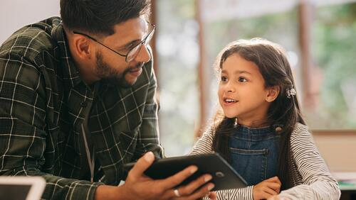 Pre-K instructor works with a student on a tablet
