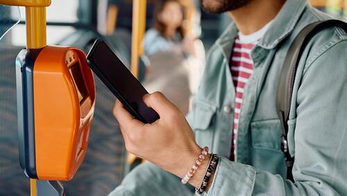 Close-up of man using phone to pay for a bus ride