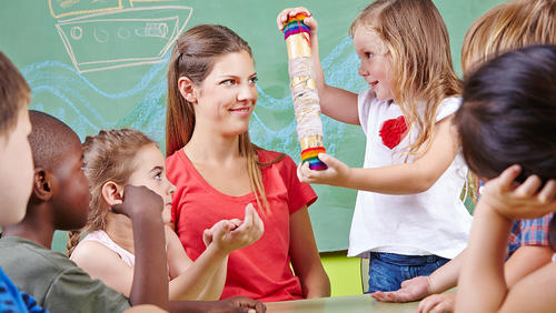 a treacher sittting among kids standing around her