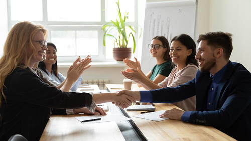 Smiling colleagues shaking hands across a conference table
