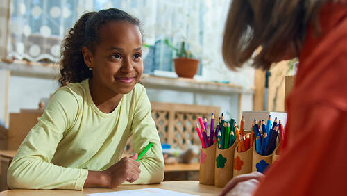 a woman is teaching a smiling middle school girl