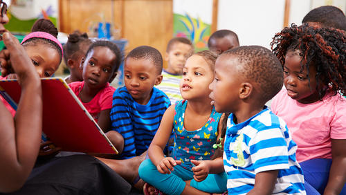 a teacher showing a book to little kids