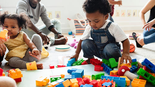 small kids are playing with toys on a floor