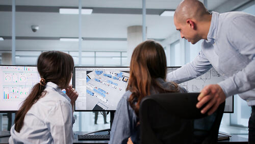 a man showing something to two young students on a computer