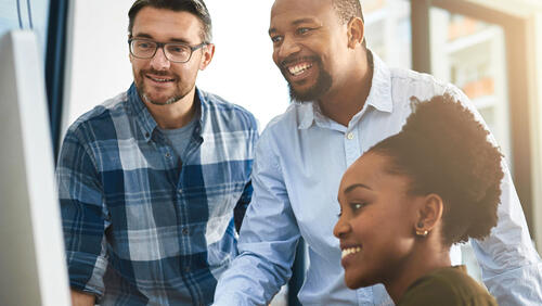 3 people college age looking at the computer monitor