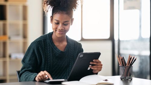 Female African-American college student using tablet and calculator
