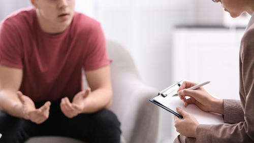 Young man speaking with a counselor as she takes notes