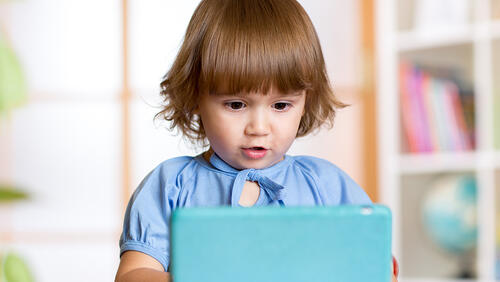 a little girl with a tablet in day care center.